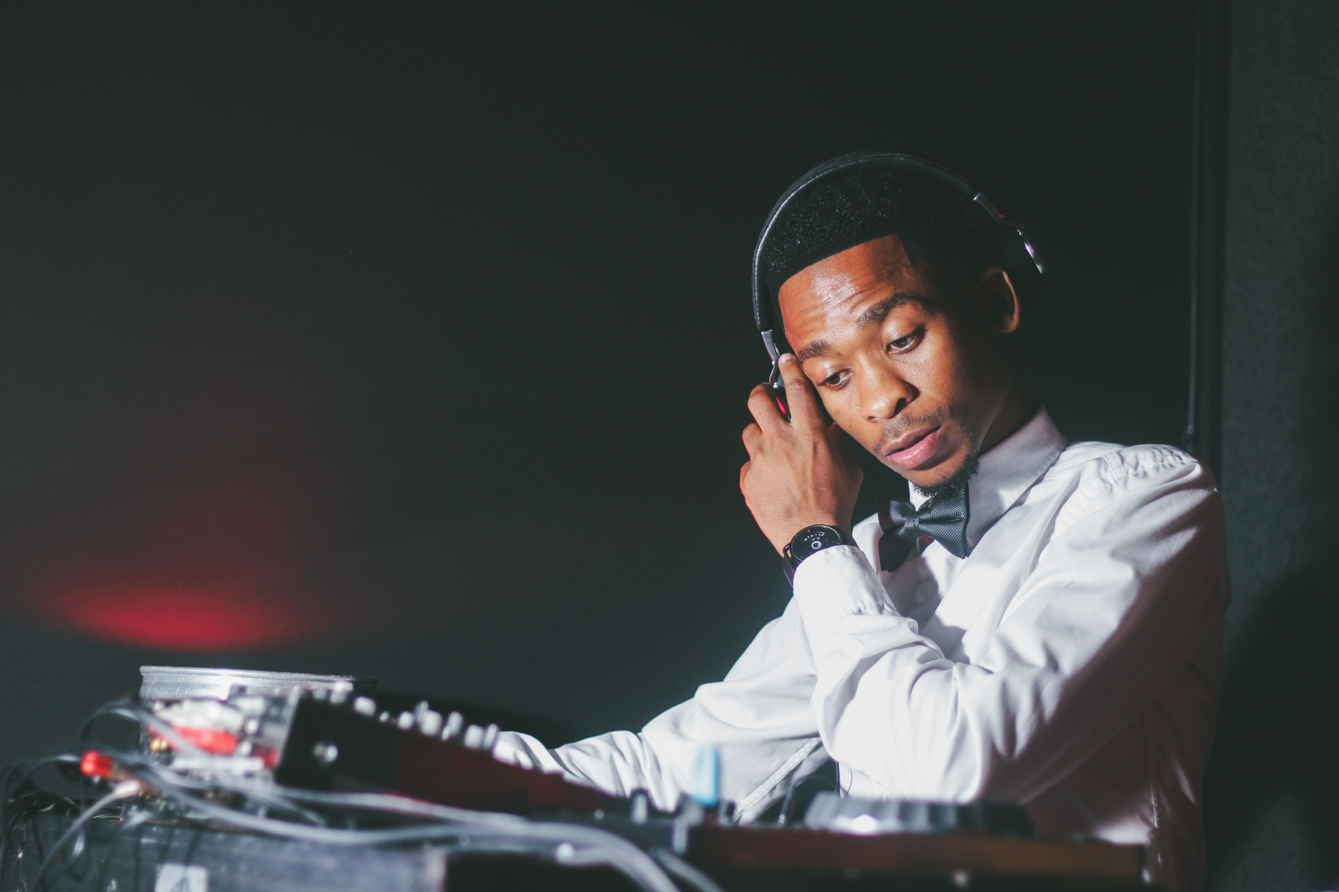 A resident DJ mixing at a club booth, illustrating Malik's weekend hustle
